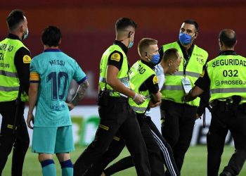 Petugas keamanan (rompi hijau) mengamankan penyusup yang hendak berfoto dengan Lionel Messi. Foto: Getty Images