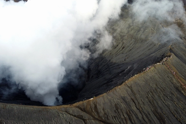 Foto udara warga berada di bibir kawah Gunung Bromo melaksanakan upacara ritual Yadnya Kasada di Tengger, Probolinggo, Jawa Timur, Sabtu (26/6). (Foto: Budi Candra Setya/ANTARA FOTO)