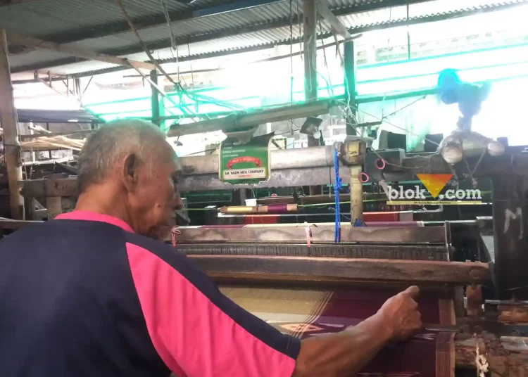 Caption : Saifudin pria lansia sedang menenun kain sarung di industri rumahan milik Ridho di Jalan Indrokilo Selatan, Lawang Kabupaten Malang (Blok-a.com / Putu Ayu Pratama S)