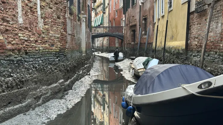 Perahu merapat di sepanjang kanal selama air surut di Venesia, Italia, Senin, 20 Februari 2023. (Luigi Costantini/AP)
