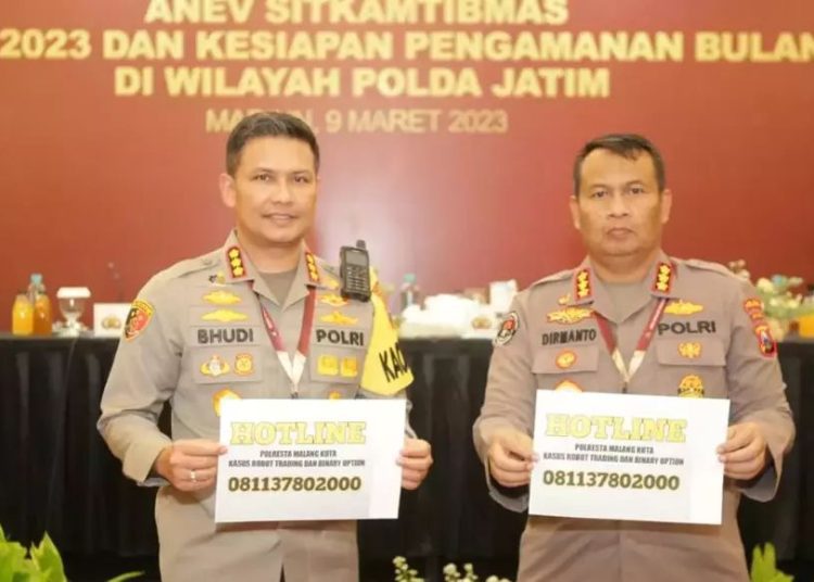 Kapolresta Malang Kota (kiri) dan Kabid Humas Polda Jatim (kanan) memegang nomor hotline pengaduan kasus investasi bodong robot trading, Kamis (9/3/2023). (Dokumen Polri)
