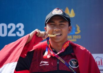 Atlet Indonesia, Rashif Amila Yaqin berpose menggigit medali emas setelah memenangkan nomor aquathlon individual putra SEA Games 2023 di Kep Town Beach, Kamboja, Sabtu (6/5/2023).(©REUTERS/Cindy Liu)