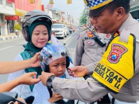 Kasatlantas Polres Mojokerto Kota AKP Mulyani memasangkan helm kepada pengendara tertib.(blok-a.com/Syahrul Wijaya)