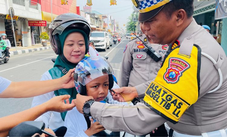 Kasatlantas Polres Mojokerto Kota AKP Mulyani memasangkan helm kepada pengendara tertib.(blok-a.com/Syahrul Wijaya)