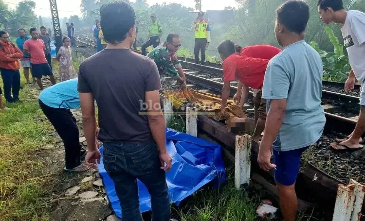 Petugas dibantu warga sekitar, mengevakuasi jasad SW, korban tertempar Kereta Api Gakayana. (blok-a.com/Fajar)