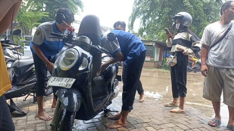 Siswa SMK YPI Darussalam 1 Cerme dari Jurusan Teknik Sepeda membantu warga yang kendaraannya mogok banjir. (Istimewa)