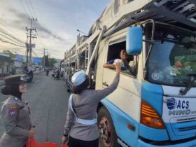 Caption : Personel Polresta Banyuwangi saat bagi-bagi Mamiri pada para pengemudi yang alami kemacetan di Pelabuhan Ketapang, Kamis (17/7/2025)(blok-a.com/Kuryanto).