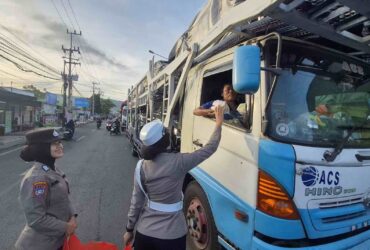Caption : Personel Polresta Banyuwangi saat bagi-bagi Mamiri pada para pengemudi yang alami kemacetan di Pelabuhan Ketapang, Kamis (17/7/2025)(blok-a.com/Kuryanto).