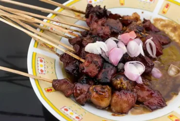 Ilustrasi hidangan sepiring sate dengan topping irisan bawang merah (dok: wikimedia)