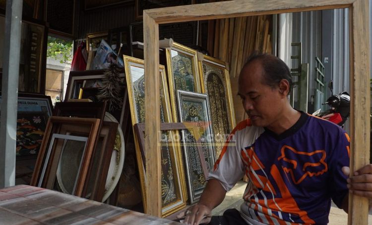Romy saat mengamplas bingkai kayu di halaman tokonya. (blok-a.com/syahrul wijaya)