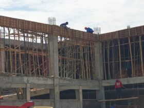 Dua pekerja tanpa APD berada di atas gedung proyek pembangunan Puskesmas Panekan Magetan.