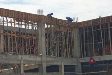 Dua pekerja tanpa APD berada di atas gedung proyek pembangunan Puskesmas Panekan Magetan.