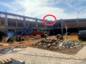 Tampak dua pekerja tanpa mengenakan APD lengkap berada diatas gedung proyek Puskesmas Panekan.