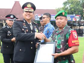 Kapolres Mojokerto Kota AKBP Herdiawan Arifianto sedang menyerahkan penghargaan kepada anggota TNI.(blok-a.com/Syahrul Wijaya)