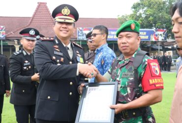 Kapolres Mojokerto Kota AKBP Herdiawan Arifianto sedang menyerahkan penghargaan kepada anggota TNI.(blok-a.com/Syahrul Wijaya)