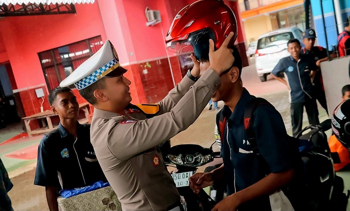 Kasat Lantas Polres Blitar, AKP Rio Anggara memberikan helm dan jas hujan kepada siswa yang mematuhi aturan. (blok-a.com/Fajar)