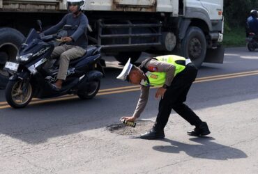 Anggota Satlantas Polres Gresik menandai sejumlah titik jalan rusak di sepanjang Jalan Raya Deandles, Kecamatan Manyar.(Ist)