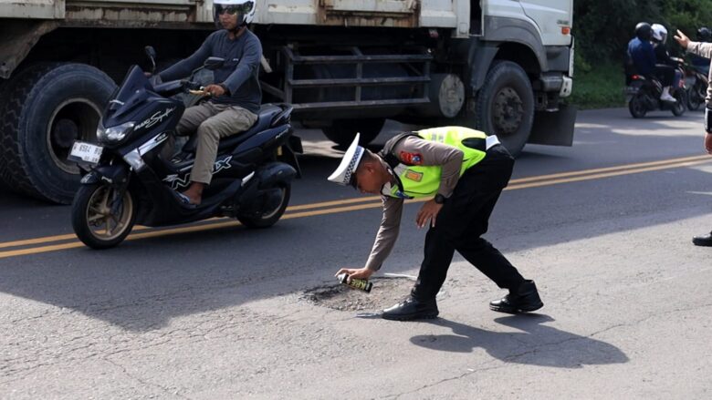 Anggota Satlantas Polres Gresik menandai sejumlah titik jalan rusak di sepanjang Jalan Raya Deandles, Kecamatan Manyar.(Ist)