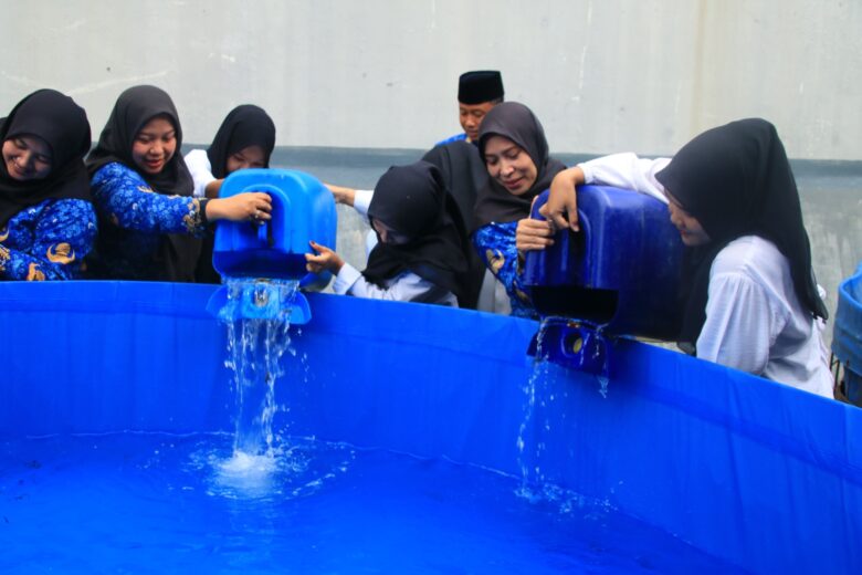 Dalam rangka mendukung ketahanan pangan sekaligus memperingati Hari Ibu ke-97, pegawai perempuan Lapas Kelas IIA Banyuwangi melepas bibit lele di kolam bioflok. (dok Humas Lapas)