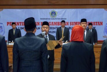 Teks foto : Bupati Gresik Fandi Akhmad Yani melantik 55 kepala sekolah serta 21 pejabat fungsional.(Ist) Pewarta : Ivan Bupati Gresik Lantik 55 Kepala Sekolah dan 21 Pejabat Fungsional Gresik, blok-a.com - Bupati Gresik Fandi Akhmad Yani mengambil sumpah dan melantik 55 kepala sekolah serta 21 pejabat fungsional di lingkungan Pemerintah Kabupaten Gresik. Pelantikan tersebut berlangsung di Ruang Mandala Bhakti Praja, Kantor Bupati Gresik, pada Senin (5/1/26). Dari total 55 kepala sekolah yang dilantik, sebanyak 53 merupakan kepala sekolah Sekolah Dasar (SD) dan 2 kepala sekolah Sekolah Menengah Pertama (SMP). Pelantikan kepala sekolah ini dilaksanakan berdasarkan Peraturan Menteri Pendidikan Dasar dan Menengah (Permendikdasmen) Nomor 7 Tahun 2025, yang menggantikan Permendikbud Nomor 40 Tahun 2021 tentang penugasan guru sebagai kepala sekolah. Penerapan regulasi tersebut bertujuan untuk mengisi kekosongan jabatan kepala sekolah yang terjadi di sejumlah satuan pendidikan. Kondisi kekosongan kepala sekolah ini tidak hanya terjadi di Kabupaten Gresik, tetapi juga hampir di seluruh wilayah Indonesia, sehingga diperlukan percepatan pengisian jabatan melalui mekanisme berbasis merit. Bupati Yani menjelaskan bahwa seluruh kepala sekolah dan pejabat fungsional yang dilantik telah melalui proses seleksi yang komprehensif, mulai dari manajemen talenta, uji kompetensi, hingga penelusuran rekam jejak. Selain itu, aspek jarak tempat tinggal dengan lokasi kerja juga menjadi pertimbangan dalam penempatan. “Panjenengan semua terpilih sesuai dengan hasil manajemen talenta dan nilai uji kompetensi yang sudah memenuhi syarat. Tapi saya juga melihat latar belakang pendidikan serta jarak rumah dengan tempat tugas. Kami tidak ingin jarak penempatan menjadi alasan menurunnya integritas dan kinerja,” ujar Bupati Yani. Kepada para kepala sekolah yang baru dilantik, Bupati Yani berpesan agar mengelola sekolah secara profesional dan akuntabel, baik dalam pengelolaan administrasi maupun pengelolaan anggaran pendidikan, seperti BOSDA dan BOSNAS. Ia juga menekankan pentingnya membangun kerja sama yang solid antara kepala sekolah dan para guru guna menciptakan lingkungan belajar yang kondusif. “Titip sekolah ini menjadi sekolah ramah anak. Tidak ada bullying, tidak ada radikalisme. Mudah-mudahan Bapak-Ibu menjadi guru yang terus dicintai oleh murid-muridnya,” pesan Bupati Yani. Dalam pelantikan tersebut, sebanyak lima peserta dari Pulau Bawean turut dilantik secara daring sebagai bentuk pemerataan pelayanan serta efisiensi pelaksanaan pemerintahan. Sebagai penutup, Bupati Yani menyampaikan bahwa kepala sekolah yang telah menjabat selama dua periode atau kurang lebih delapan tahun akan segera didorong untuk mengikuti uji sertifikasi pengawas. Kebijakan ini bertujuan untuk membuka ruang regenerasi dan pengembangan karier di bidang pendidikan.(Ivn)