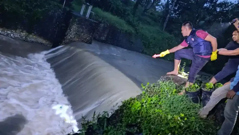 Anggota Polsek Glagah, saat lakukan olah TKP penemuan mayat laki-laki tanpa identitas di aliran Sungai Gelung (Dam Pugak), Desa Kemiren, Minggu (18/1/2026) malam. (dok Polsek Glagah untuk blok-a.com)