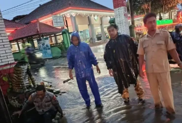 Anggota Polsek Glenmore Banyuwangi melakukan penanganan atas genangan air akibat curah hujan tinggi, sepanjang Jalan Raya Jember, Senin (9/2/2026)(blok-a.com/Kuryanto).
