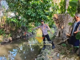 Kanit Intelkam Polsek Singojuruh, Aiptu Firdaus saat menunjukkan lokasi ditemukan Muawanah, lansia yang meninggal dunia di sungai belakang rumahnya, Senin (06/07/2026)(foto: Blok-a.com/Kuryanto)
