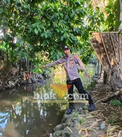 Kanit Intelkam Polsek Singojuruh, Aiptu Firdaus saat menunjukkan lokasi ditemukan Muawanah, lansia yang meninggal dunia di sungai belakang rumahnya, Senin (06/07/2026)(foto: Blok-a.com/Kuryanto)