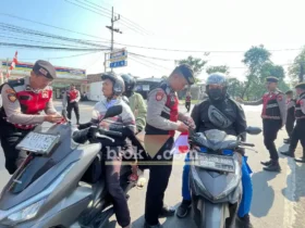 Terlihat anggota Satsamapta Polres Mojokerto saat membagikan bendera merah putih kepada pengguna jalan (foto: Blok-a.com/Syahrul Wijaya)