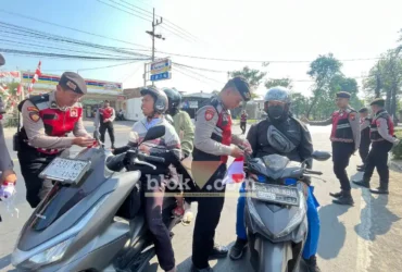 Terlihat anggota Satsamapta Polres Mojokerto saat membagikan bendera merah putih kepada pengguna jalan (foto: Blok-a.com/Syahrul Wijaya)
