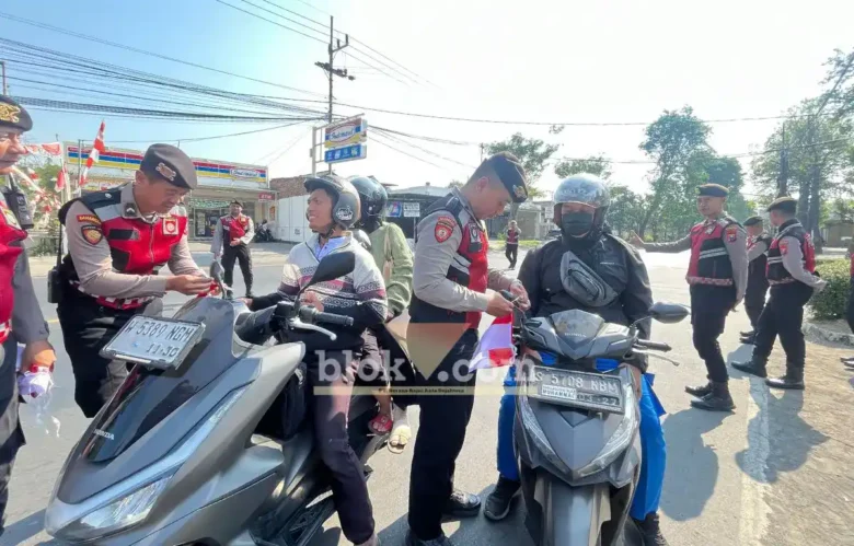 Terlihat anggota Satsamapta Polres Mojokerto saat membagikan bendera merah putih kepada pengguna jalan (foto: Blok-a.com/Syahrul Wijaya)
