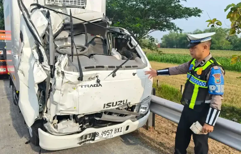 Petugas PJR 3 Polda Jatim Aipda Agus saat di lokasi dan truk boks yang hancur bagian depannya usai tabrak truk tangki.(Foto: PJR 3 Polda Jatim)